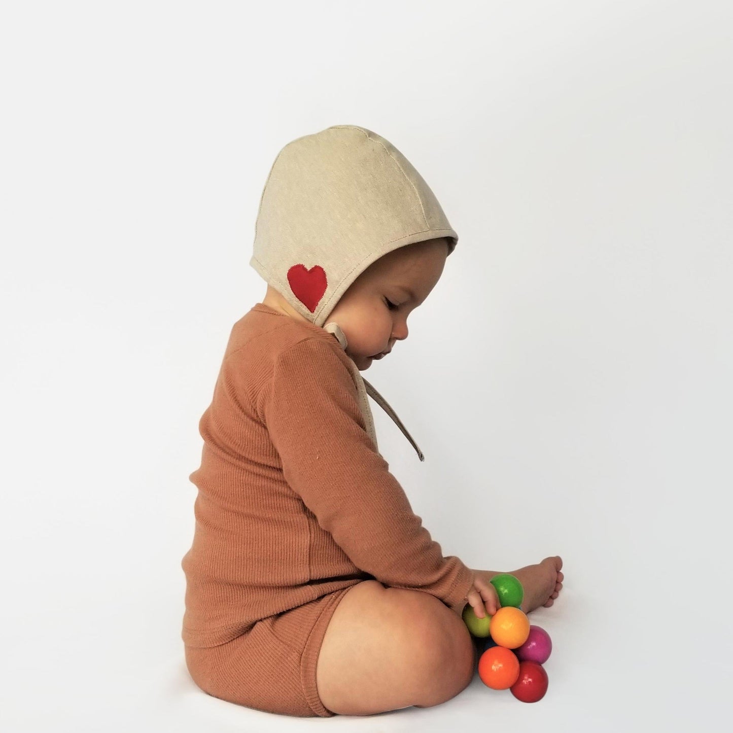 Baby wearing heart embroidered bonnet.