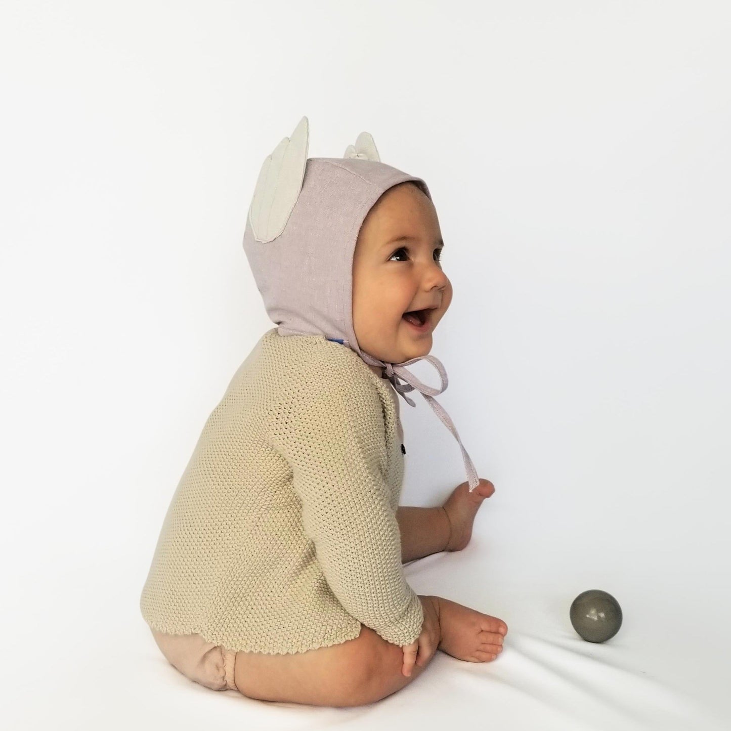 Baby wearing lilac bonnet with glitter wings