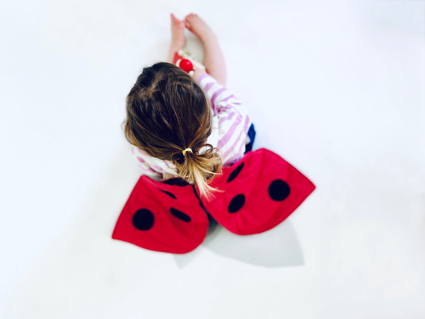 Toddler wearing ladybug dress as part of a Montessori toy chest.