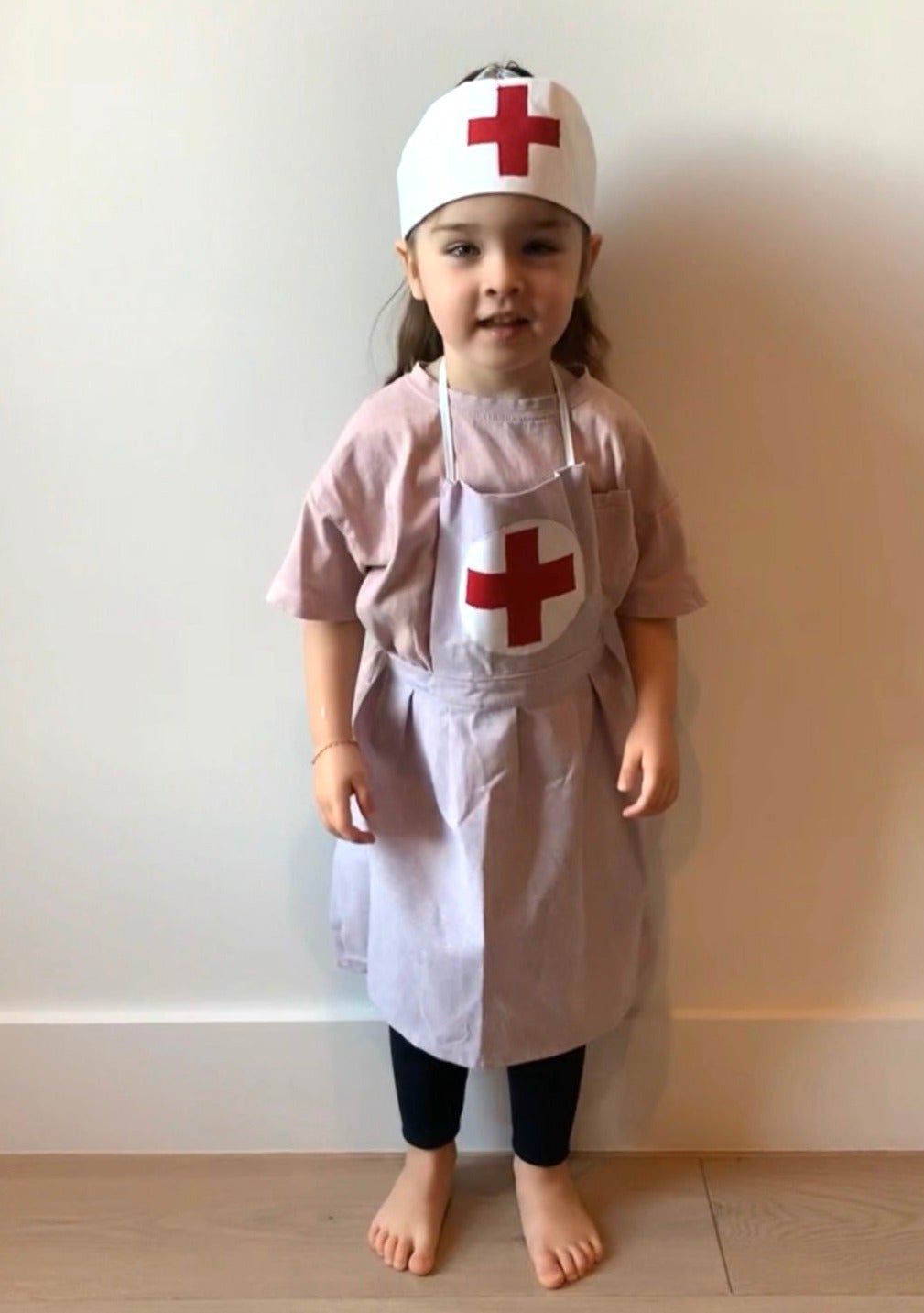 Girl wearing handmade nurse dress and hat playing dress up