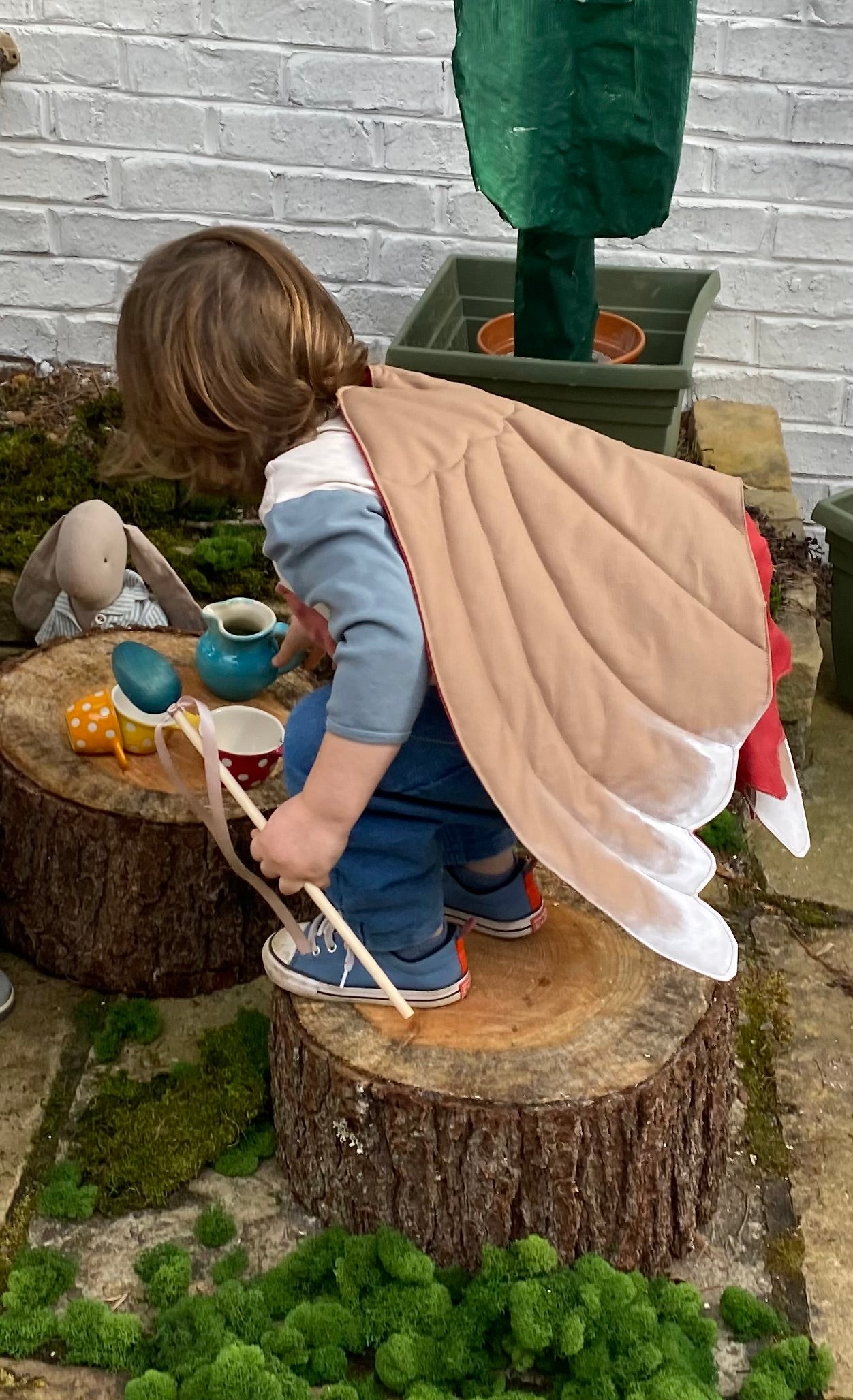 Child playing pretend with bird dress up wings.